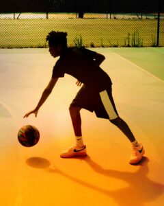 http://Basketball%20player%20on%20court%20in%20Paris.%20Nets%20and%20court%20in%20background.%20Backlit%20and%20warm%20colours.